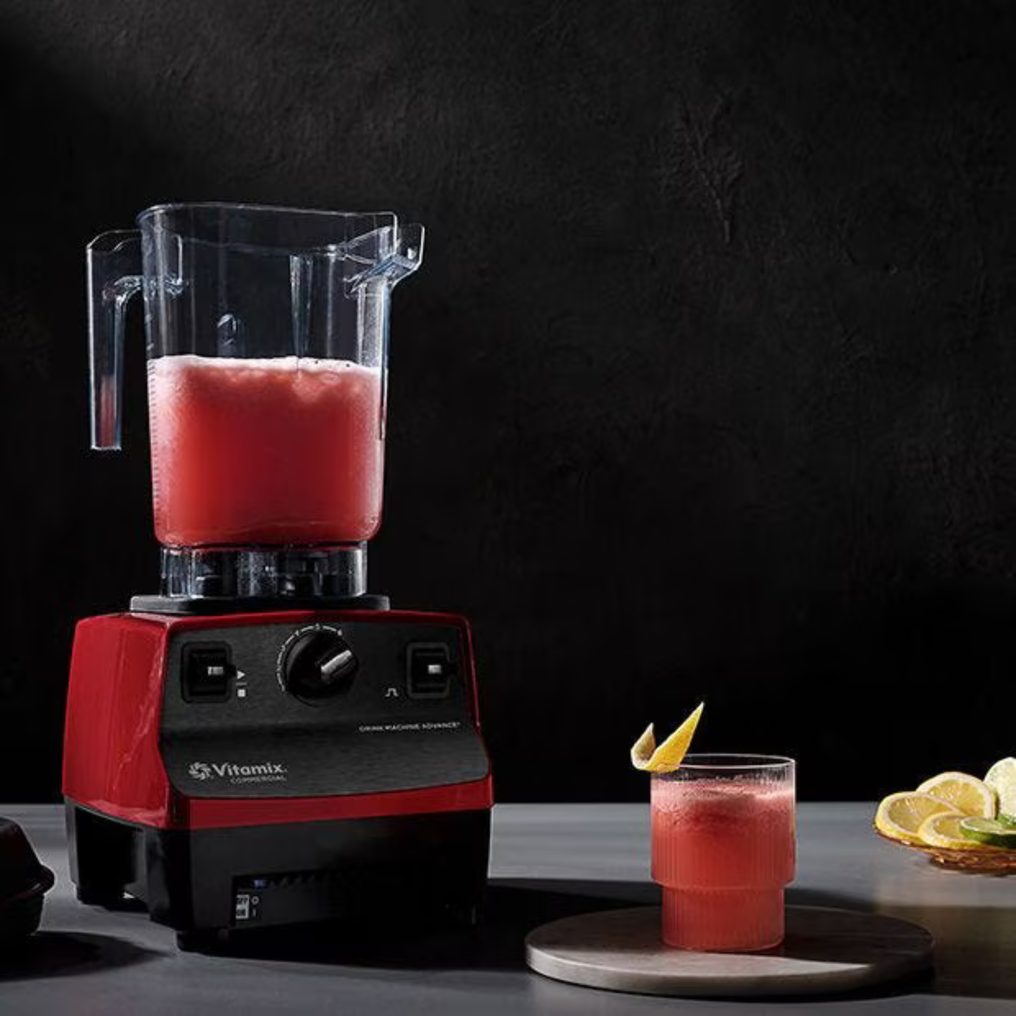 Vitamix Drink Machine Advance Blender Red 1.4L | Blenders Direct with a red smoothie next to a glass of the same smoothie on a dark background