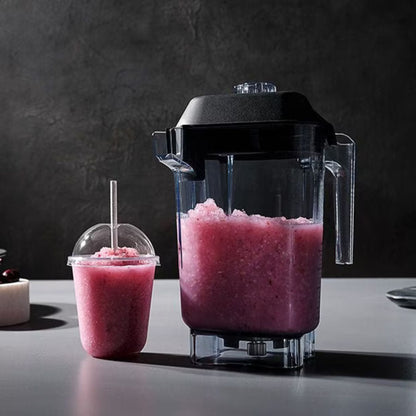 Blender with a pink slushie and a cup on a dark surface