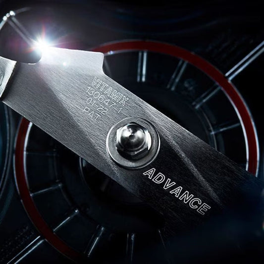 Close-up of a tool with 'Vitamix' branding and 'Advance' text against a dark background.
