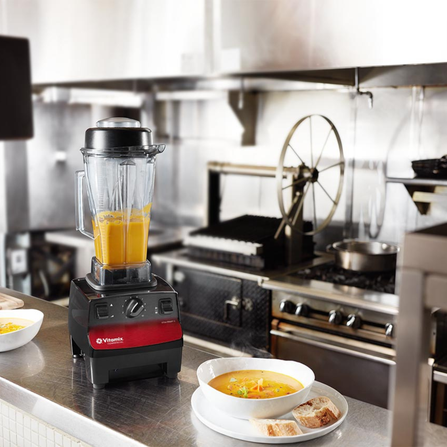 Vitamix Vita-Prep 3 | Blenders Direct with orange juice on a kitchen counter next to a bowl of soup and bread.