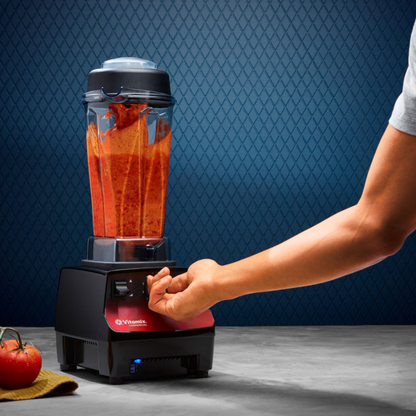 Person using a Vitamix Vita-Prep 3 | Blenders Direct with a red liquid on a blue patterned background